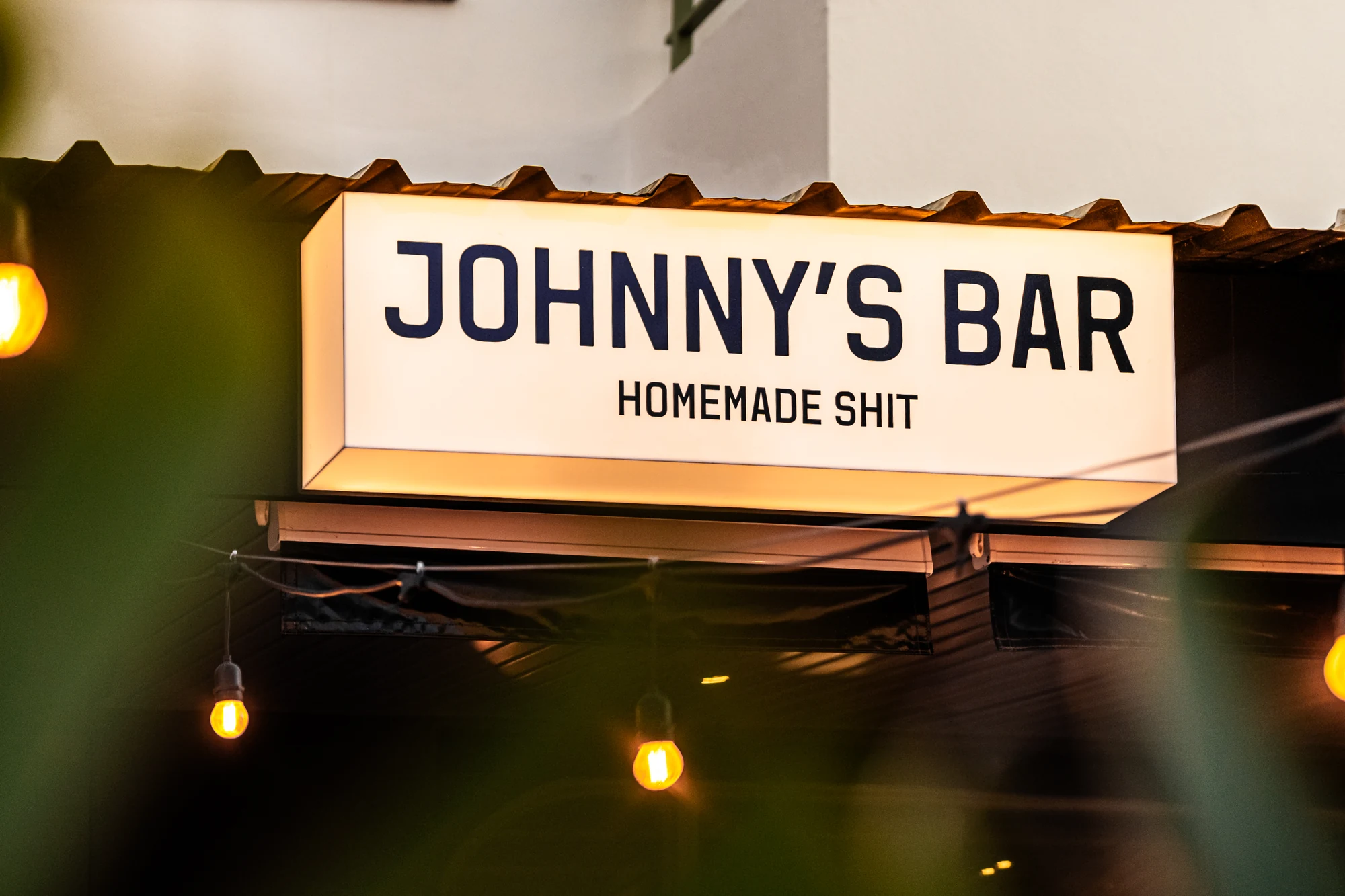 Rótulo luminoso de Johnny's Bar al anochecer en Cala de Bou